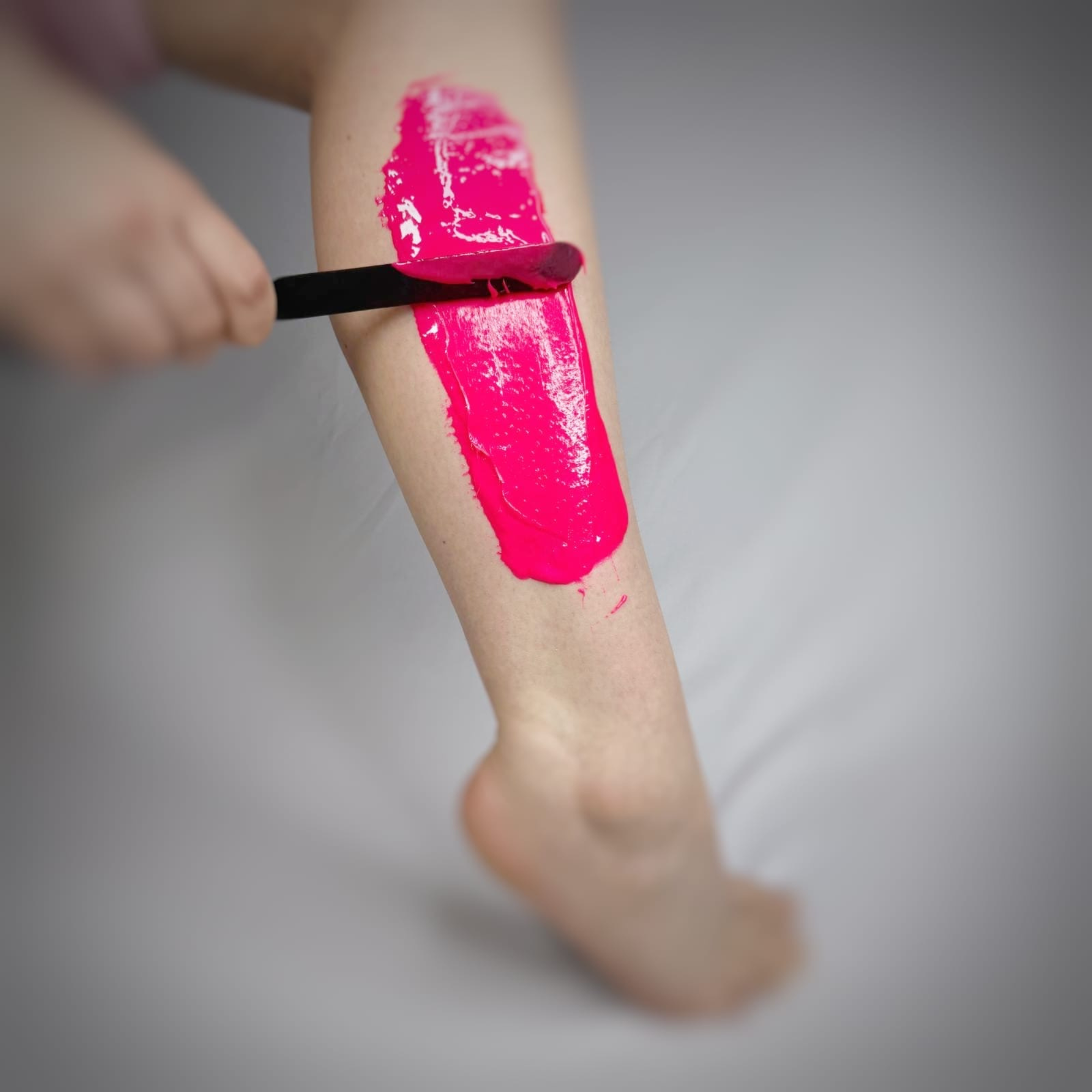 Dragonfruit Pink Sugar Paste for hair removal being applied with a black applicator on a white background
