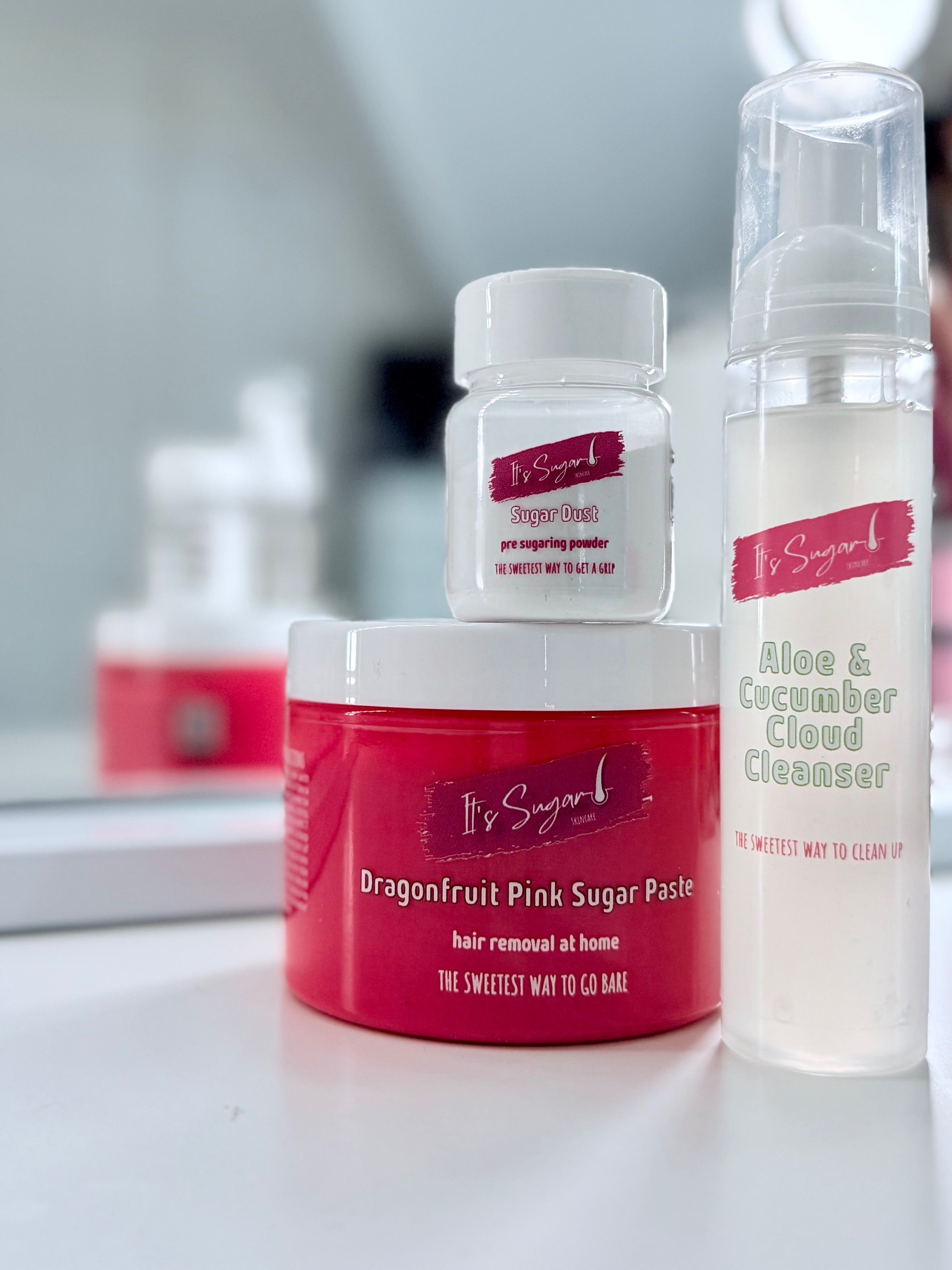 Collection of hair removal products including a jar, bottle, and container on a white surface, mirror in background
