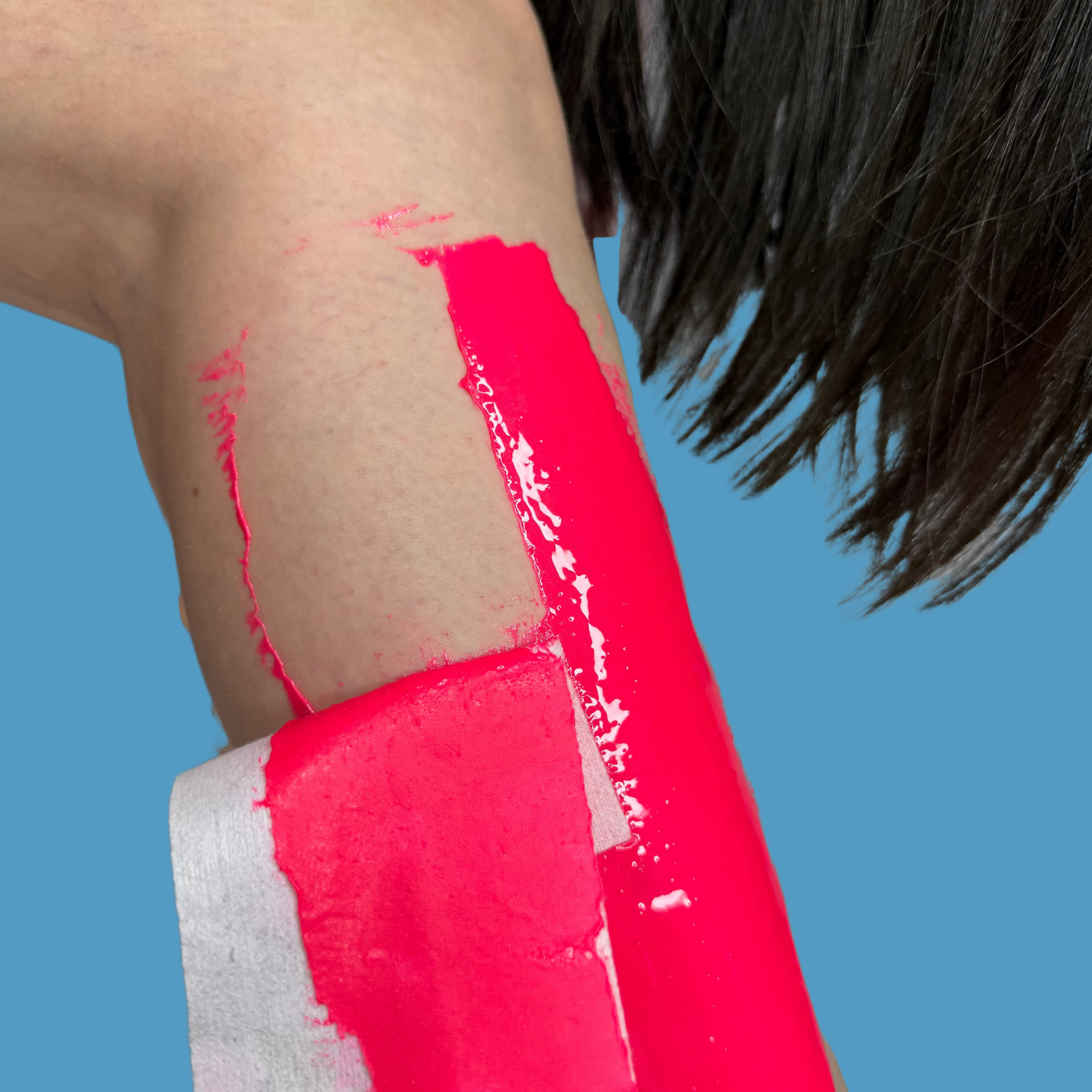 Dragonfruit Pink Sugar Paste applied to leg, reusable strip half been removed. Teen girls long straight hair hangs in the blue background.