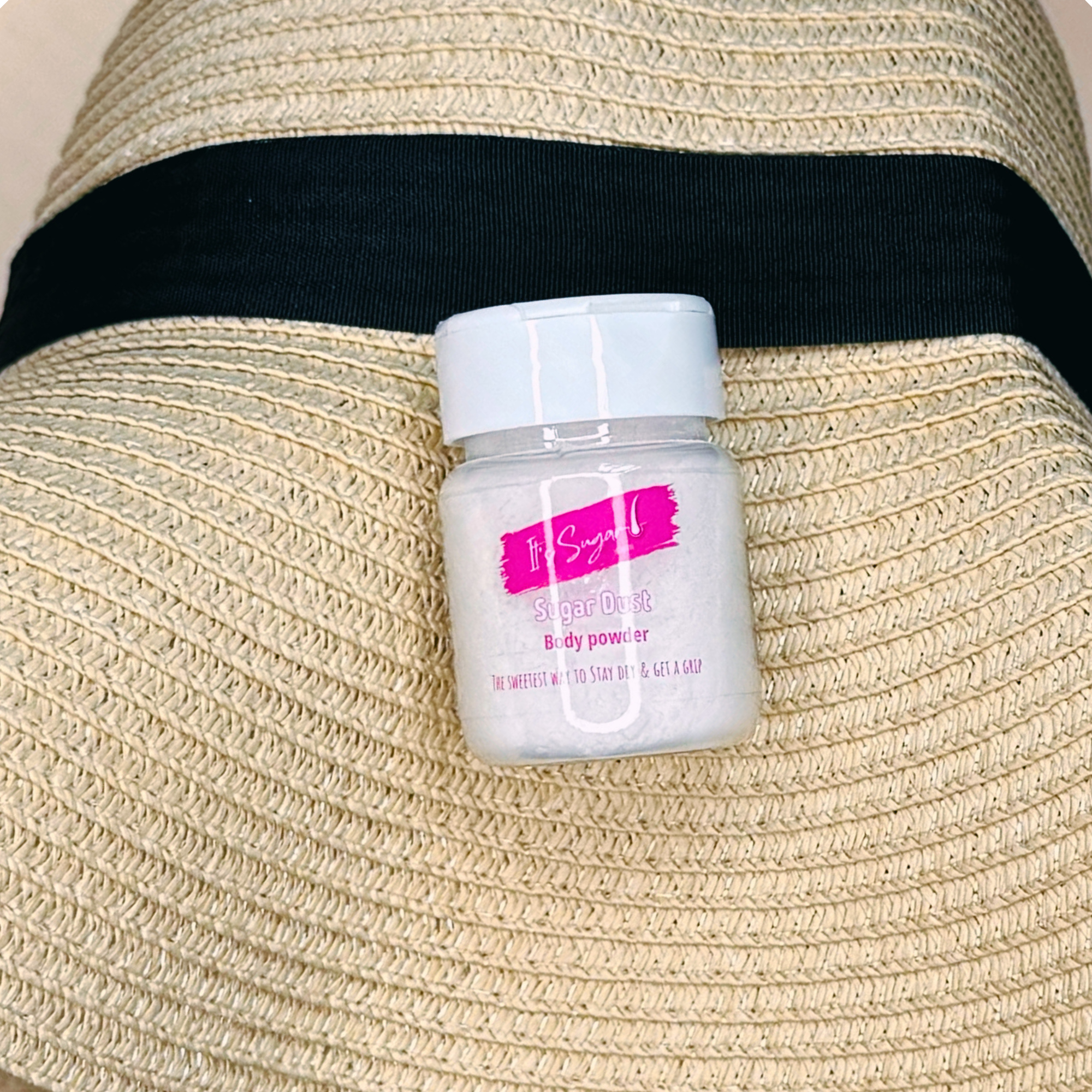 Jar of Sugar Dust Body Powder on a straw bag with a black strap