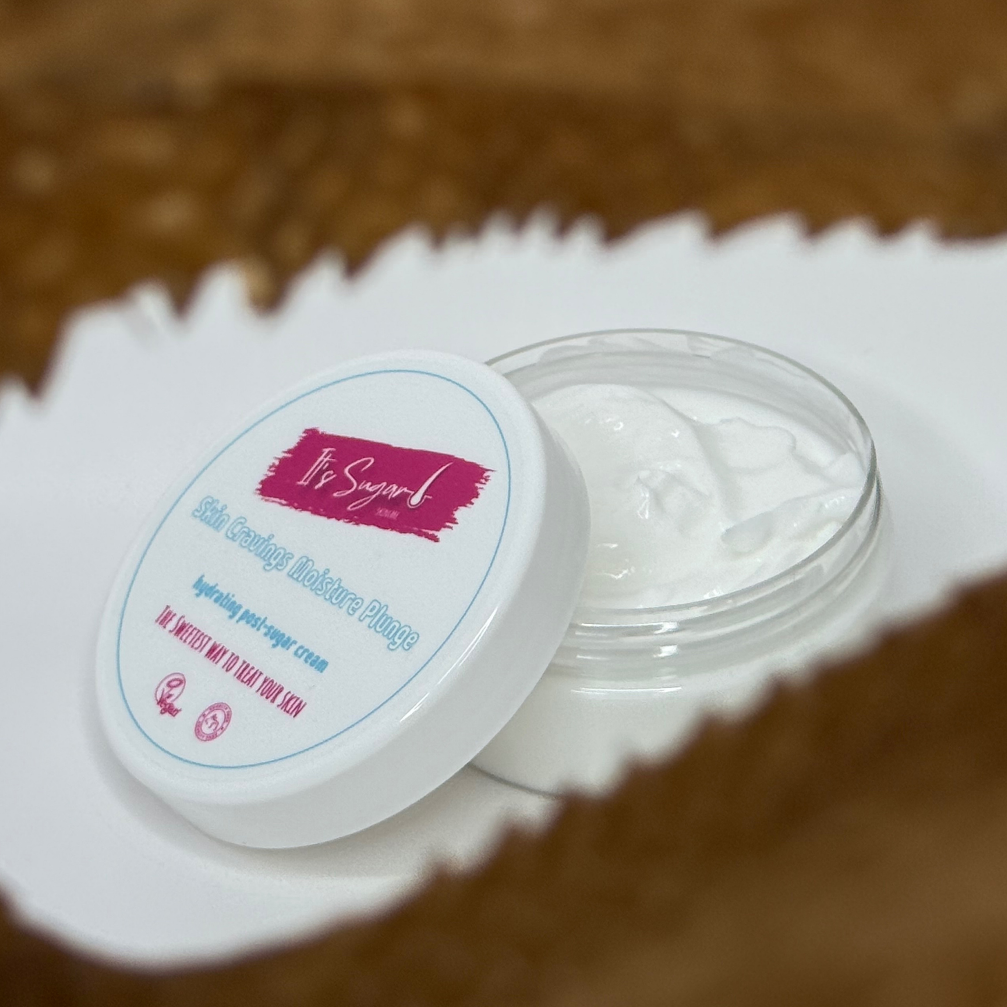 Moisturiser with lid off, displaying cream contents with a blurred image edge